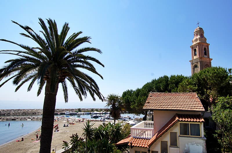 A beautiful view of Church, a palm tree and sandy beach in San Lorenzo al Mare