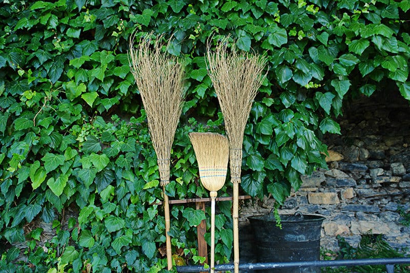Brooms are standing next to some plants in Triora, town which is often called a village of the witches