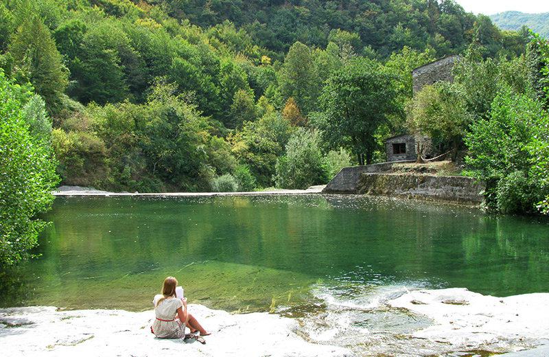 A girl reading a book at the lake of Molini di Triora
