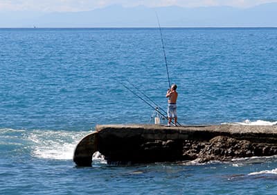 A man is fishing on the stones in Recco